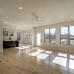 An Open Concept Living Space With Hardwood Floors And Large Windows